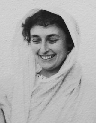 Black and white photograph of head and shoulders of woman in white headscarf